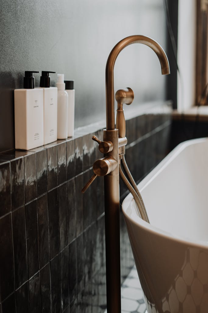 Bronze faucet with sprayer on white ceramic tub.